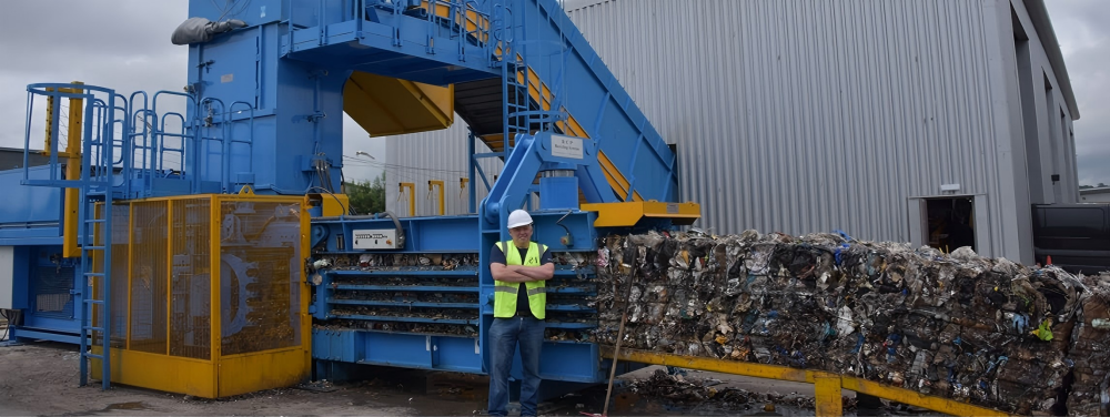 Heavy duty scrap metal baler in an industrial recycling facility